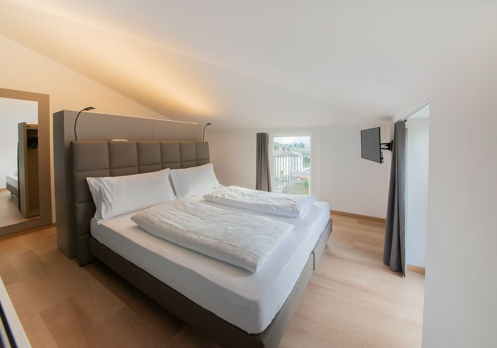 Junior Suite con balcone | Una spaziosa suite mansardata con più privacy e una vista aperta sulle montagne per un soggiorno di autentico relax.