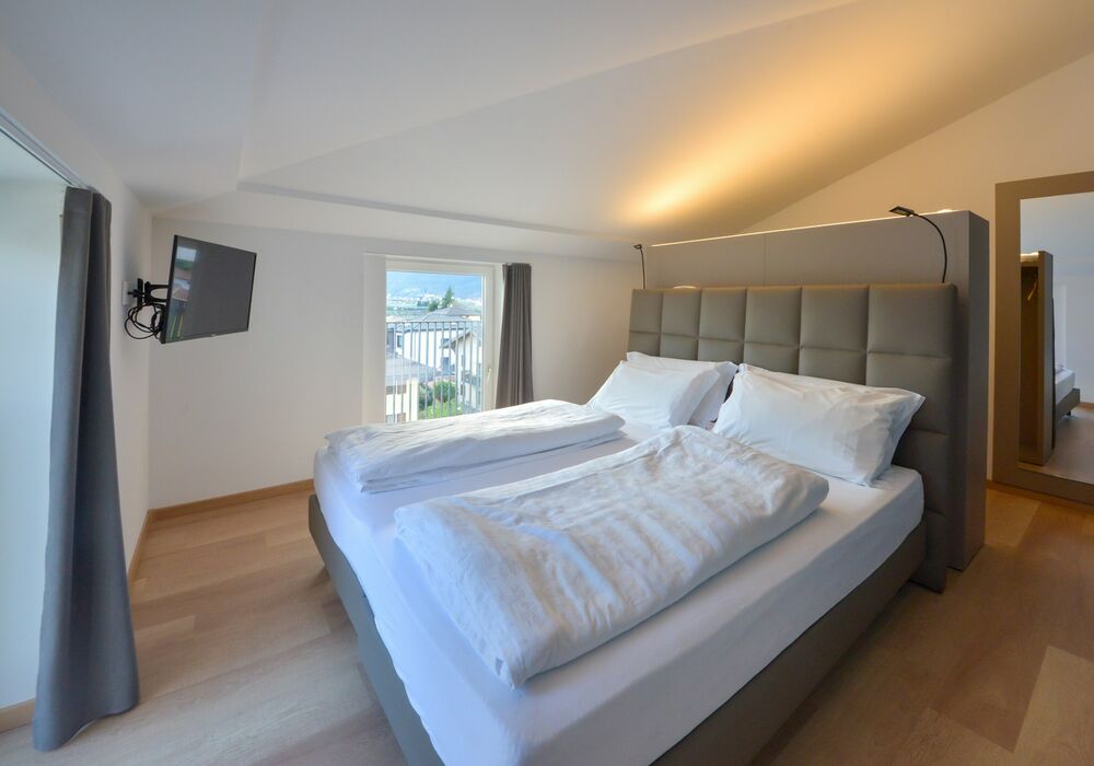 Junior Suite con balcone | Una spaziosa suite mansardata con più privacy e una vista aperta sulle montagne per un soggiorno di autentico relax.