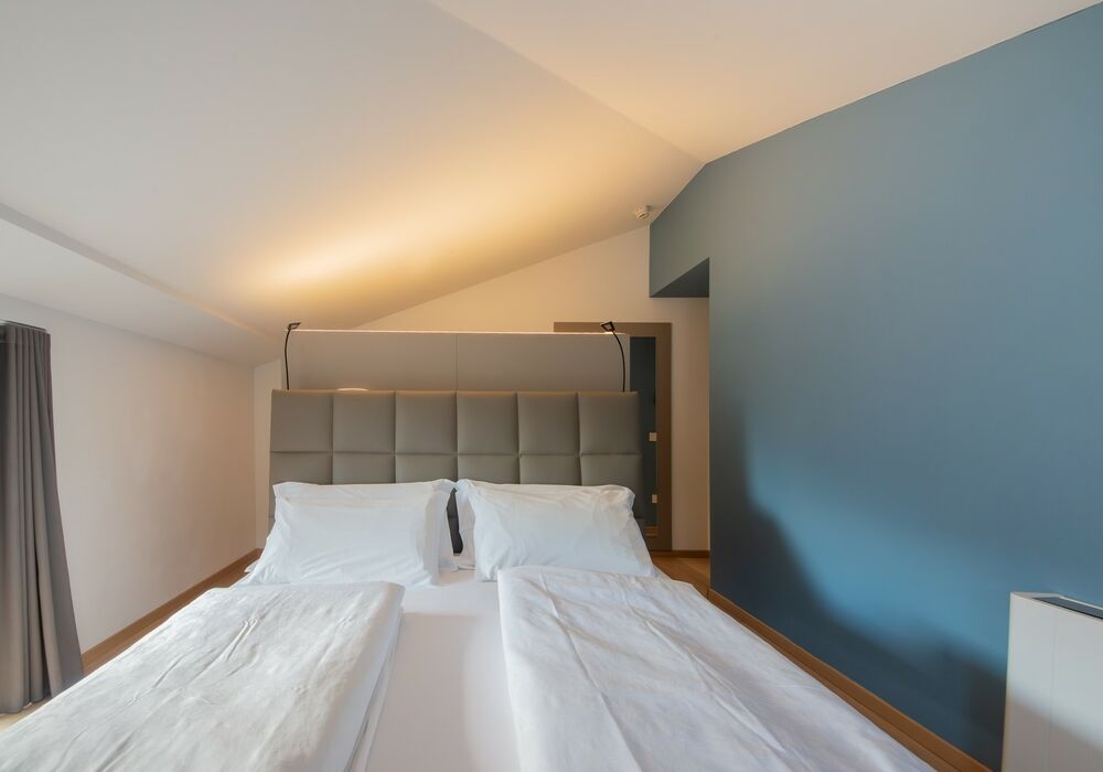 Junior Suite con balcone | Una spaziosa suite mansardata con più privacy e una vista aperta sulle montagne per un soggiorno di autentico relax.